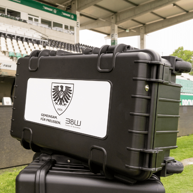 Schwarzer B&W International Schutzkoffer mit Preußen Münster Branding im Stadion, robuste Transportlösung in Vereinskooperation.