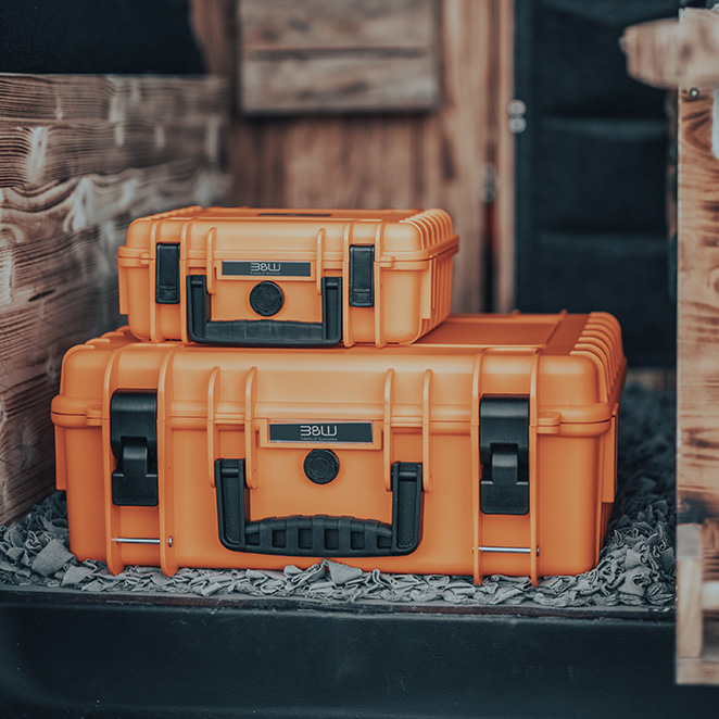 Zwei B&W International Koffer in leuchtendem Orange, stapelbar und robust, ideal für den sicheren Transport von Ausrüstung in verschiedenen Größen.