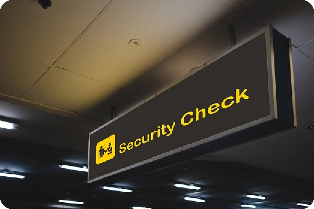 Leuchtendes "Security Check"-Schild in einem Flughafen, mit gelbem Text und Symbolen für den Sicherheitsbereich.