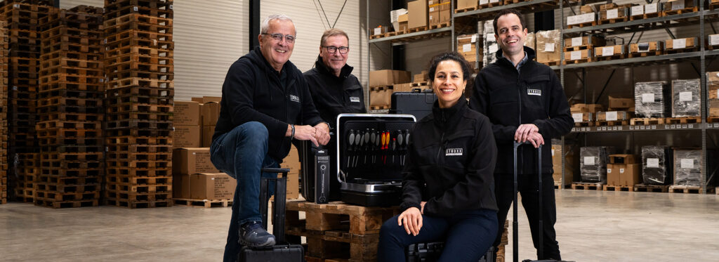 Das Stroxx-Team in einer Lagerhalle mit B&W International Werkzeugkoffern, bereit für den Einsatz im Handwerk und in der Industrie.