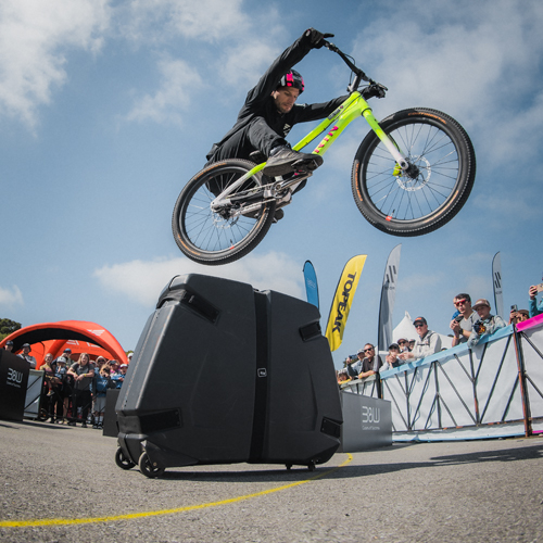 Trial-Biker Duncan Shaw bei der Sea Otter Classic 2024 in Aktion – Sprung mit dem Fahrrad über einen B&W Transportkoffer, fotografiert von Dave Mackison.